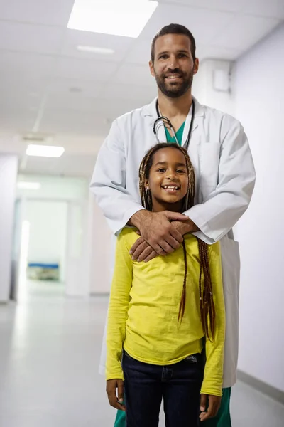 ハンサムな小児科医先生笑顔とともに彼の女の子患者に病院 — ストック写真