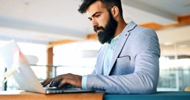 Ofiste bilgisayar üzerinde çalışan genç yakışıklı işadamı