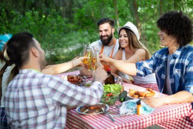 Küçük bir arkadaş grubu alkol içip barbekü partisinde yemek yiyor.