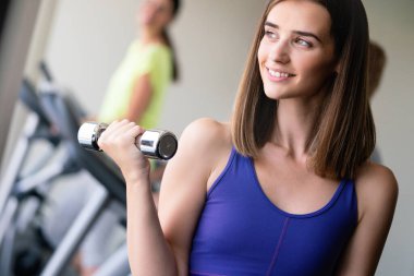 Spor salonunda halterle egzersiz yapan güzel bir kadın.