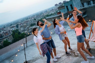 Bir grup mutlu genç arkadaş dans ediyor ve birlikte eğleniyorlar.