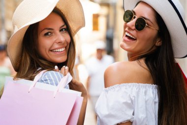 Güzel alışveriş kadınları alışveriş torbalarını tutarken ve yaz tatilinde eğlenirken mutlu olurlar.