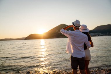 Kumsalda yürüyen bir çift. Genç mutlu insanlar kumsalda yürüyor gülümsüyor, yaz tatilinin tadını çıkarıyor.