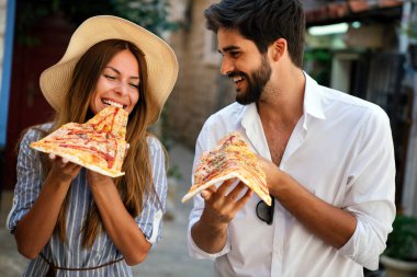 Tatildeyken pizza yiyen mutlu çift.