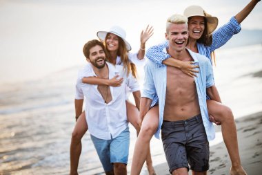 Bir grup arkadaş gün batımında sahilde yürürken eğleniyorlar.