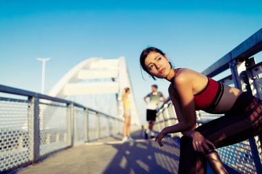Açık havada koştuktan sonra dinlenen atletik formda genç bir kadının portresi.