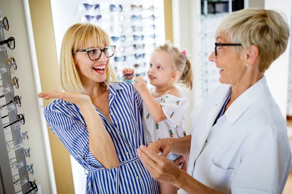 光学店でガラスを選ぶ幸せな若い家族 — ストック写真