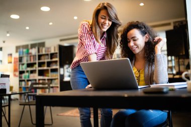 İnsanlar, bilgi, eğitim okulu konsepti. Bir grup mutlu öğrenci kitap okuyor ve kütüphanede sınava hazırlanıyor.