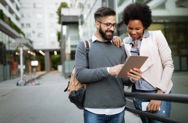 Neşeli çift eğleniyor, dışarıda elektronik tabletle konuşuyorlar.