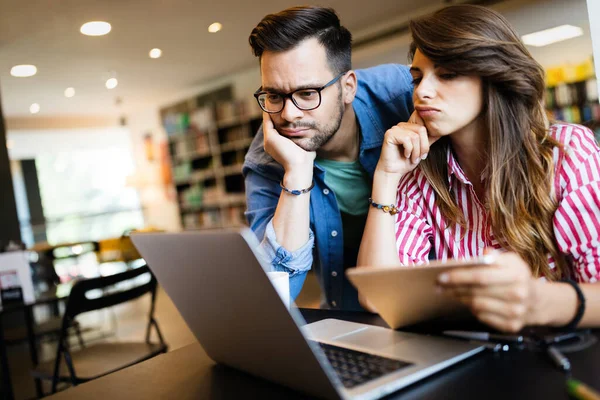 Üniversite, eğitim, üniversite ve eğitim konsepti. Bir grup yorgun öğrenci kütüphanede öğreniyor.