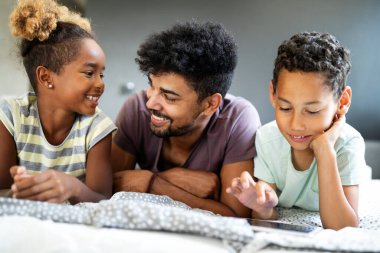 Mutlu bir aile evde vakit geçirir ve tabletteki bir şeye bakar. Teknoloji, aile kavramı.