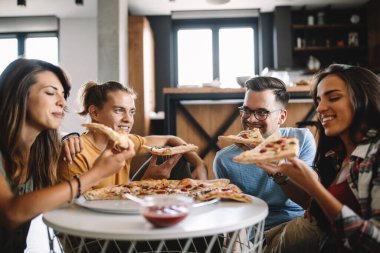 Neşeli bir arkadaş grubu evde eğleniyor, pizza yiyor..