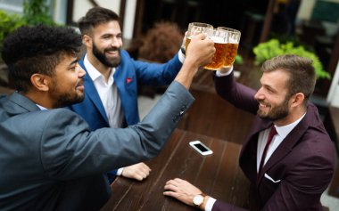 Neşeli eski dostlar, iş adamları bar tezgahında bira içip eğleniyorlar..
