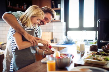 Güzel, genç ve güzel bir çift evde sağlıklı yemekler pişirirken konuşup gülümsüyor.