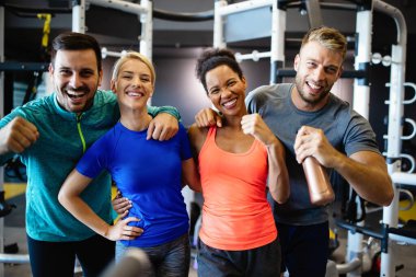 Spor salonunda egzersiz yapan bir grup sağlıklı genç arkadaş.