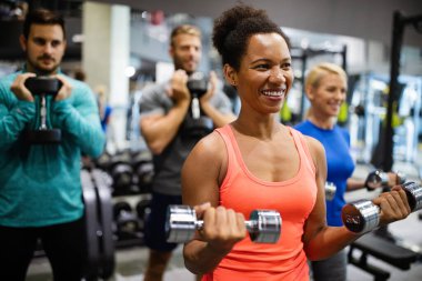 Spor salonunda egzersiz yapan bir grup sağlıklı genç arkadaş.