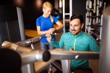 Spor salonunda makineyle egzersiz yapan mutlu genç adam.