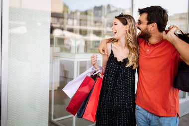 Şehirde alışveriş torbaları olan genç ve mutlu bir çift.
