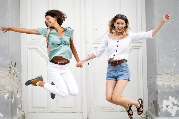 Две Счастливые Молодые Женщины Прыгают Смеются Вместе Открытом Воздухе — стоковое фото