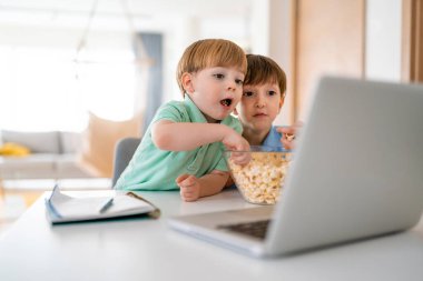 Oynayan sevimli çocuklar, evde dizüstü bilgisayardan film izliyorlar. Dijital, teknoloji bağımlılığı kavramı.