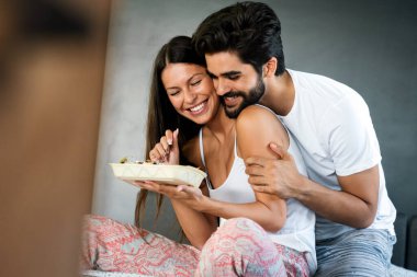 Genç beyaz çift yatakta romantik bir kahvaltı yapıyor..