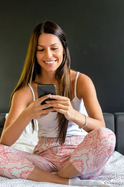 Aantrekkelijke Glimlachende Vrouw Met Behulp Van Smartphone Terwijl Ontspannen Thuis — Stockfoto