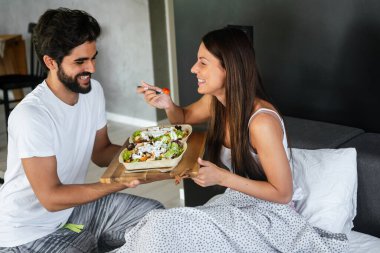 Mutlu adam kahvaltıyı yatağındaki güzel kız arkadaşına getiriyor.