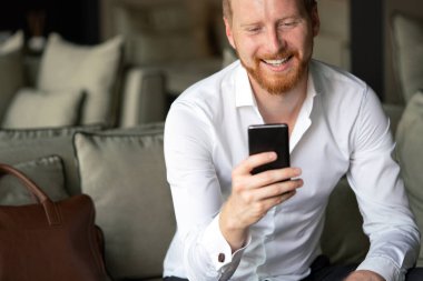 Genç işadamı cep telefonuyla mesaj gönderiyor. İş, teknoloji, insan kavramı