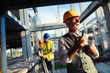 İnşaat alanı kontrol belgeleri ve iş akışı üzerine grup halinde çalışan mimarlar ve mühendisler.