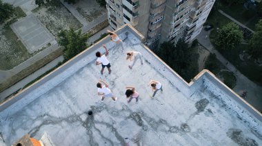 Bir grup zinde insan çatıda antrenman yapıyor.