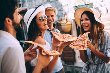Arkadaşlar dışarıda eğleniyor, yaz tatilinde pizza yiyorlar.