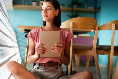 Güzel öğrenci ya da iş kadınının portresi dijital tablet kullanarak günlük kıyafetle.