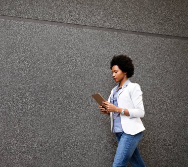 Tabletle şehirde yürüyen gülümseyen Afrikalı kadının portresi. Yoğun şehir hayatı konsepti