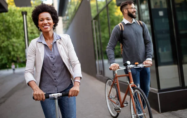 Δύο Χαμογελαστοί Επιχειρηματίες Που Οδηγούν Ηλεκτρικά Σκούτερ Ποδήλατο Μπροστά Από — Φωτογραφία Αρχείου