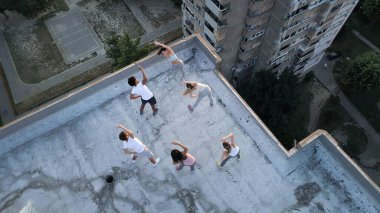 Bir grup zinde insan çatıda antrenman yapıyor.