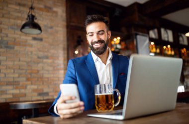 Kafede oturan başarılı bir girişimcinin portresi bir dizüstü bilgisayar üzerinde çalışıyor..