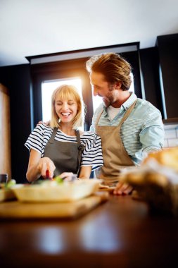 Evdeki mutfakta birlikte yemek pişiren mutlu genç bir çiftin portresi..