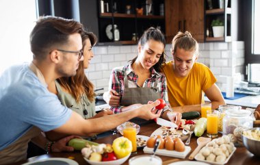 Bir grup mutlu insan, arkadaşlar mutfakta eğleniyor, birlikte yemek pişiriyorlar.