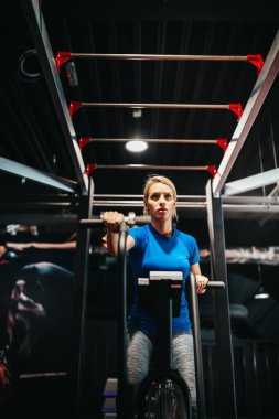 Bisikletli kadın spor salonunda kardiyo çalışması yapıyor. Spor bisikletinde egzersiz yapan formda genç bir bayan..