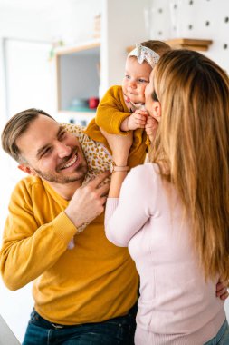 Gülümseyen genç ebeveynler ve çocukları evde çok mutlular.