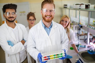 Laboratuvarda çalışan genç öğrenciler ve kimya bilimcileri.