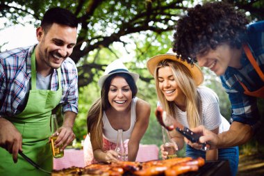 Arkadaşlar doğada barbekü yaparken eğleniyorlar.