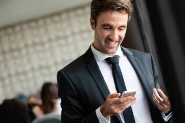 Ofiste cep telefonu kullanan başarılı bir iş adamı. İş, teknoloji, insan kavramı