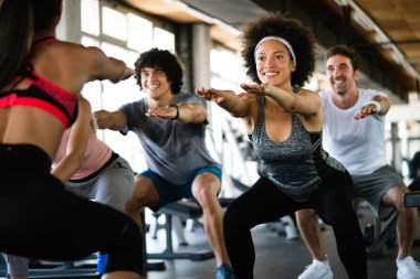Spor salonunda egzersiz yapan bir grup formda genç.