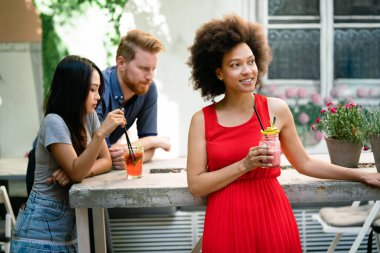 Çeşitli mutlu arkadaşlar yaz aylarında kafede eğleniyor, konuşuyor, gülümsüyor.