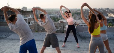 Bir grup zinde insan çatıda antrenman yapıyor.