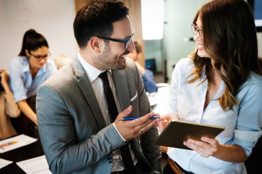 Modern ofisteki mutlu iş arkadaşları tablet kullanıyor ve birlikte çalışıyorlar.