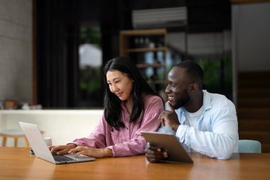 Başarılı çeşitlilik, çok ırklı bağımsız çift, birlikte dizüstü bilgisayarda çalışarak, tropik iklimin huzurlu ortamının tadını çıkarıyor..