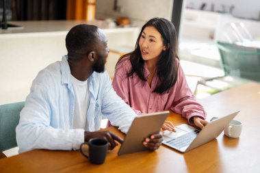 Başarılı çeşitlilik, çok ırklı bağımsız çift, birlikte dizüstü bilgisayarda çalışarak, tropik iklimin huzurlu ortamının tadını çıkarıyor..