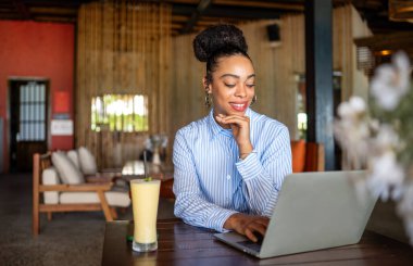 Happy freelancer enjoying a nutritious breakfast of smoothie and salad while using a laptop and working